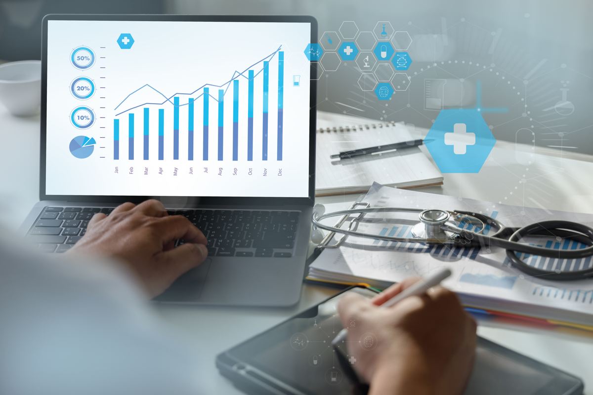 Clinician reviewing health analytics charts on a laptop beside a stethoscope